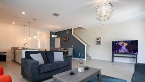 Un salon moderne avec un canapé gris, une table basse en bois et un téléviseur fixé au mur.