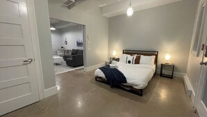 Quarto com cama, mesas de cabeceira e uma porta.