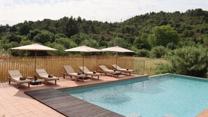A swimming pool with lounge chairs and umbrellas, surrounded by a wooden deck and a bamboo fence. - Louis Henry (Saint-Pierre-des-Champs)
