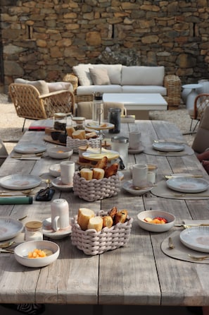 A wooden table set for a meal with various dishes, bread, and utensils. - Louis Henry (Saint-Pierre-des-Champs)