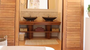 A bathroom with wooden shutters, a large mirror, two sinks, and a bed with a white bedspread. - Louis Henry (Saint-Pierre-des-Champs)