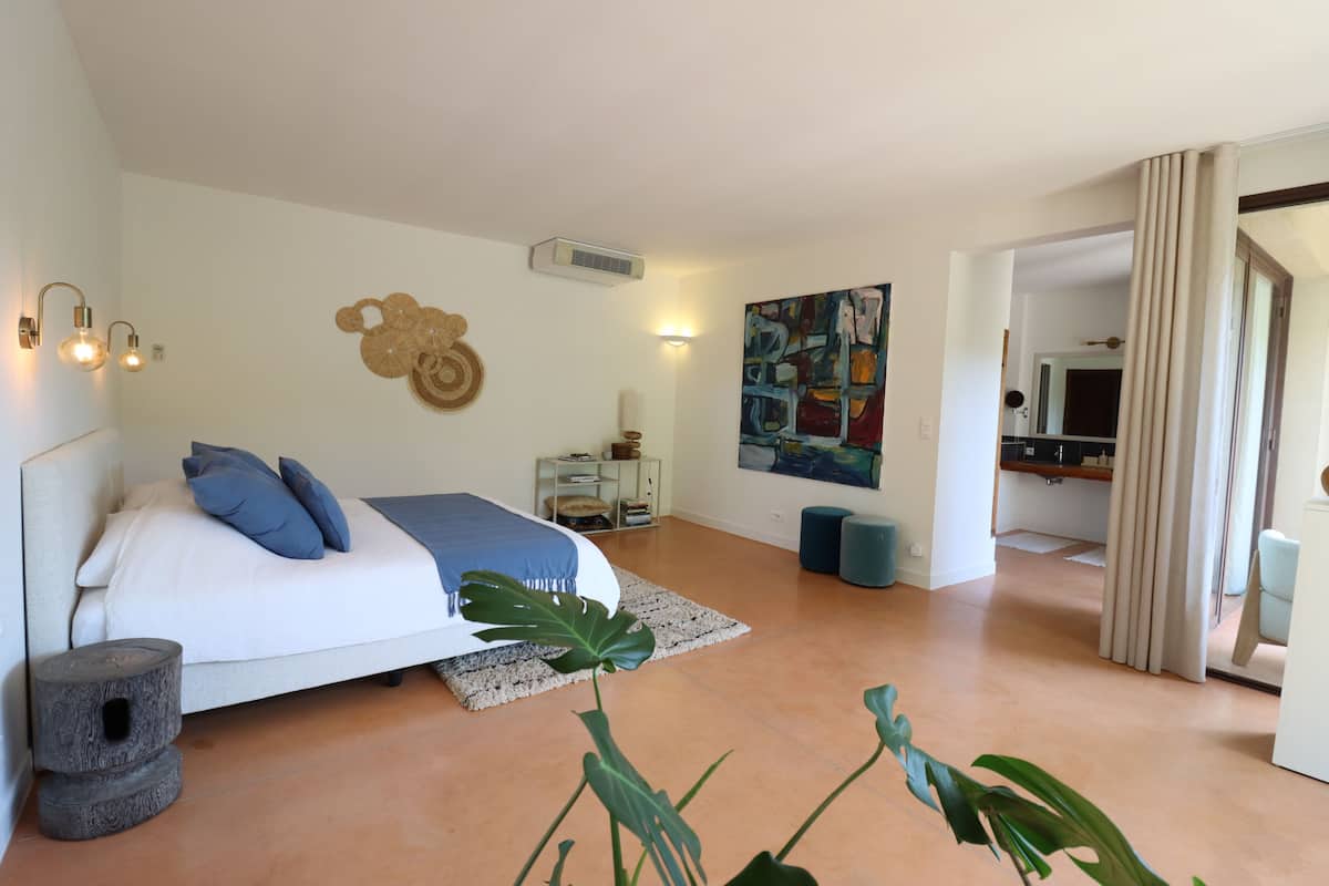 Un dormitorio con cama, mesita de noche, decoración en la pared y vista a otra habitación.