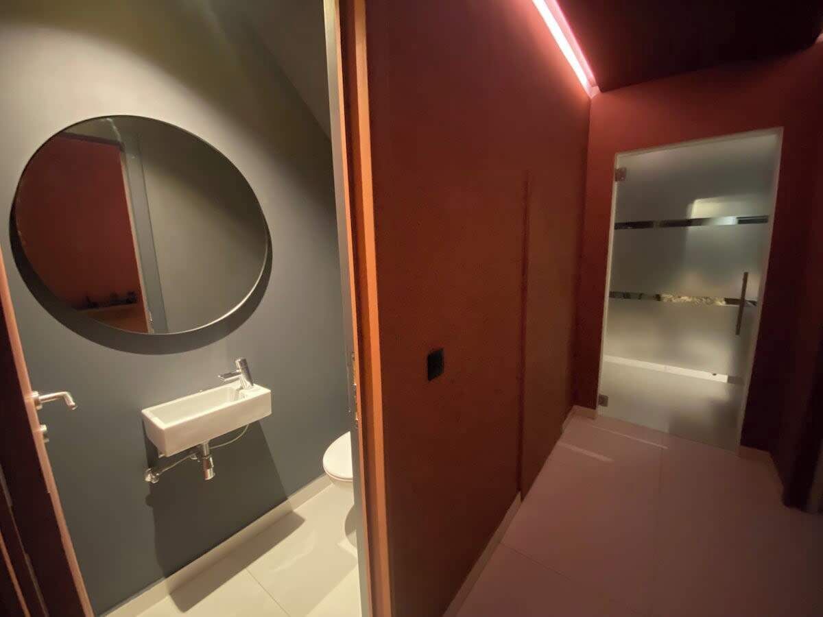 Een moderne badkamer met een ronde spiegel, een wit wastafelmeubel en een douchecabine met glazen wanden.