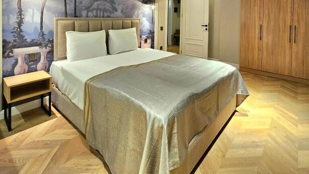 Ein Schlafzimmer mit einem großen Bett, einem Nachttisch, einem Kleiderschrank und einem Wandgemälde.