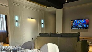Ein moderner Essbereich mit einem runden Tisch, gedeckt für vier Personen, einer Couch und einem an der Wand befestigten Flachbildfernseher.