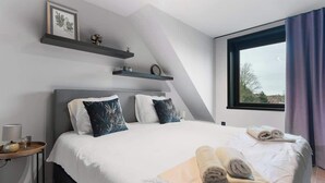 A modern bedroom with a large bed, two pillows, a bedside table with a lamp, and a window with curtains. - Elegant & Spacious House close to Center (Kortrijk)