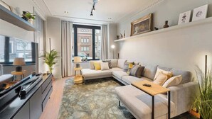 A modern living room with a sectional sofa, a flat-screen TV, a coffee table, and a decorative rug. - Elegant & Spacious House close to Center (Kortrijk)