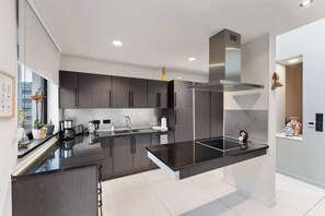 Une cuisine moderne avec des meubles de couleur sombre, un plan de travail noir et des appareils électroménagers en acier inoxydable.