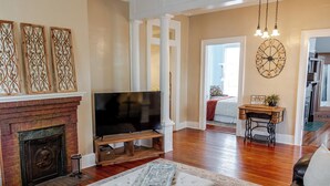 Una sala de estar con chimenea, televisor, reloj y máquina de coser.