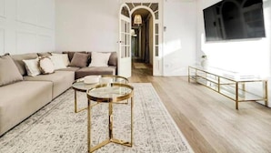 Een woonkamer met een bank, twee bijzettafels, een vloerkleed en een televisie.