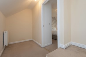 A room with a radiator, a door leading to another room, and a carpeted floor. - Toast Stays - Durham View (Spennymoor)