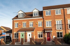 A row of terraced houses with distinct front doors, a clear sky, and a visible street. - Toast Stays - Durham View (Spennymoor)