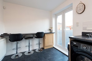A kitchen with three black bar stools, a washing machine, and a wooden cabinet. - Toast Stays - Durham View (Spennymoor)