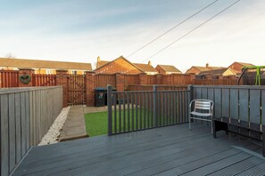 A backyard with a wooden deck, a metal gate, and a green lawn. - Toast Stays - Durham View (Spennymoor)