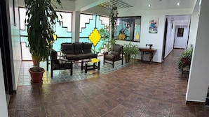 A spacious lobby with a sofa set, a sewing machine, and potted plants. - hotel killa (Urubamba)