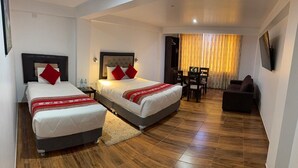 A hotel room with two beds, a sofa, a TV, and a dining area. - hotel killa (Urubamba)