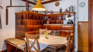 A dining area with a wooden booth, a table with a white tablecloth, and a yellow pendant light. - Apartment 'Landliebe' with Mountain View, Shared Terrace, and Wi-Fi (Münstertal)