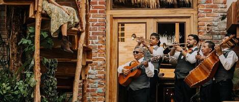 A brick building with a wooden staircase, a pool, and a group of musicians playing instruments.