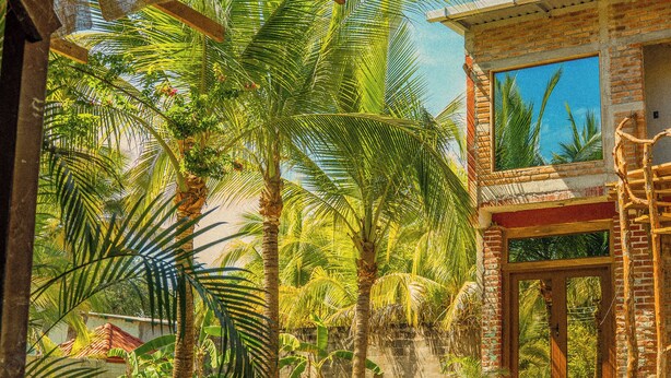 A pool area with a stone border, palm trees, and a wooden pergola. - Casona Tunan (Mizata)