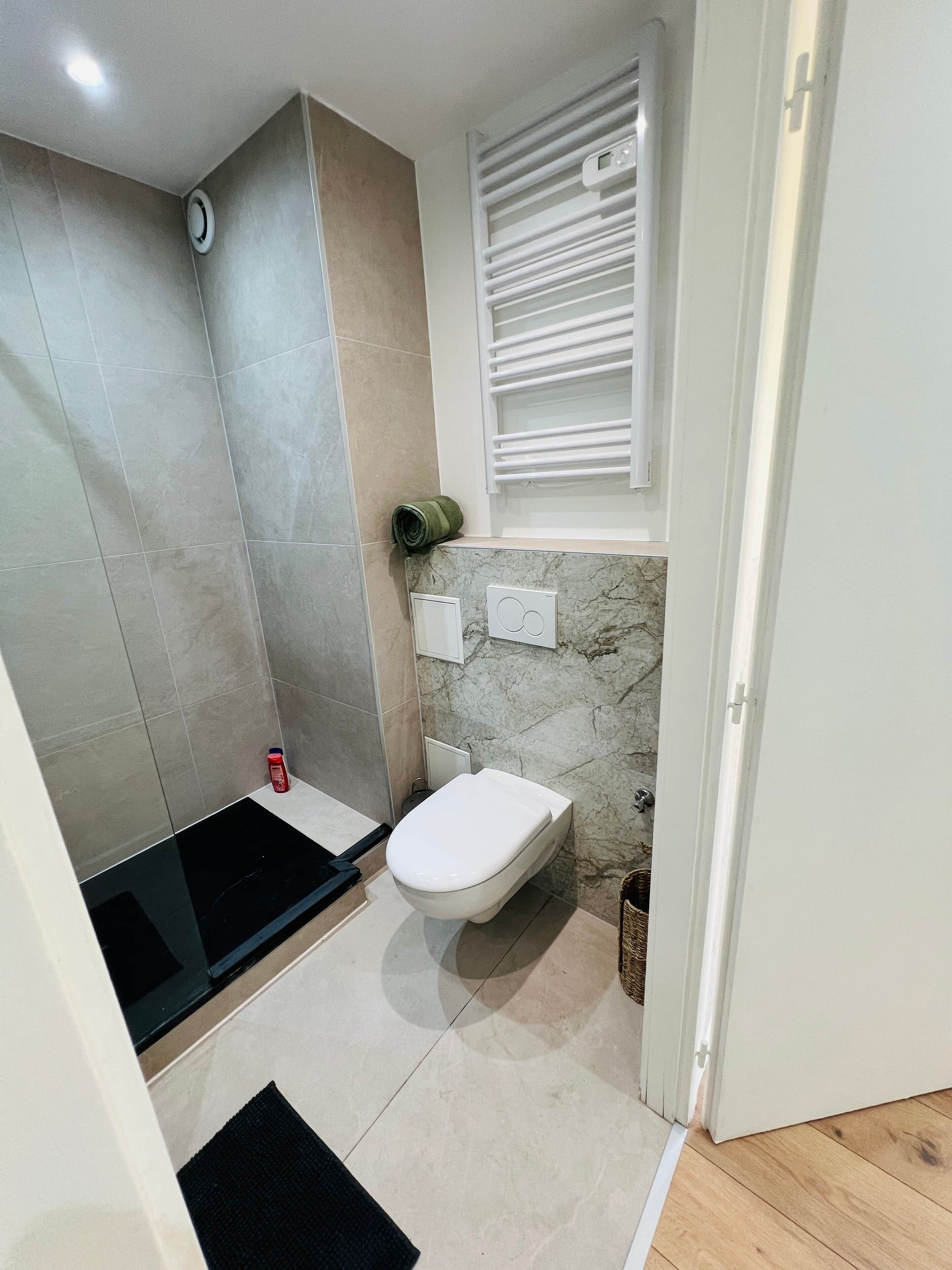 Un baño pequeño con ducha, inodoro y un ventanal con persianas.
