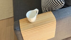 Ein modernes Wohnzimmer mit einem grauen Sofa, einem Holztisch und einer weißen Tasse auf dem Tisch.