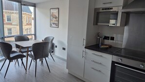 Cozinha moderna com área de refeições, janelas amplas e vista para prédios.
