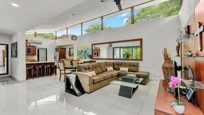 A spacious living area with a large sectional sofa, a dining table, and a kitchen in the background. - Casa Lumina – Contemporary 3-Bedroom Villa with Private Pool - 6 Guests (Playas del Coco)