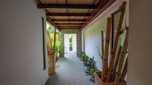A hallway with a wooden ceiling, potted plants, and bamboo sticks on the right. - Casa Lumina – Contemporary 3-Bedroom Villa with Private Pool - 6 Guests (Playas del Coco)