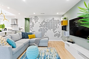 A modern living room with a sectional sofa, a flat-screen TV, and a world map wall art.