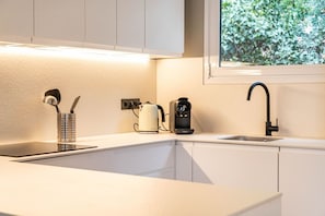 A modern kitchen with a white countertop, a kettle, a coffee maker, and a faucet. - Villa Atardecer—15' from Barcelona / BBQ / Pool (CT)