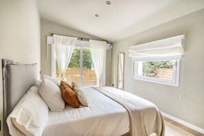 A bedroom with a bed, curtains, a window, and a view of the outdoors. - Villa Atardecer—15' from Barcelona / BBQ / Pool (CT)