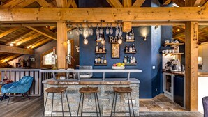 Un'area bar rustica con travi in legno, una parete in pietra e un bancone con sgabelli.