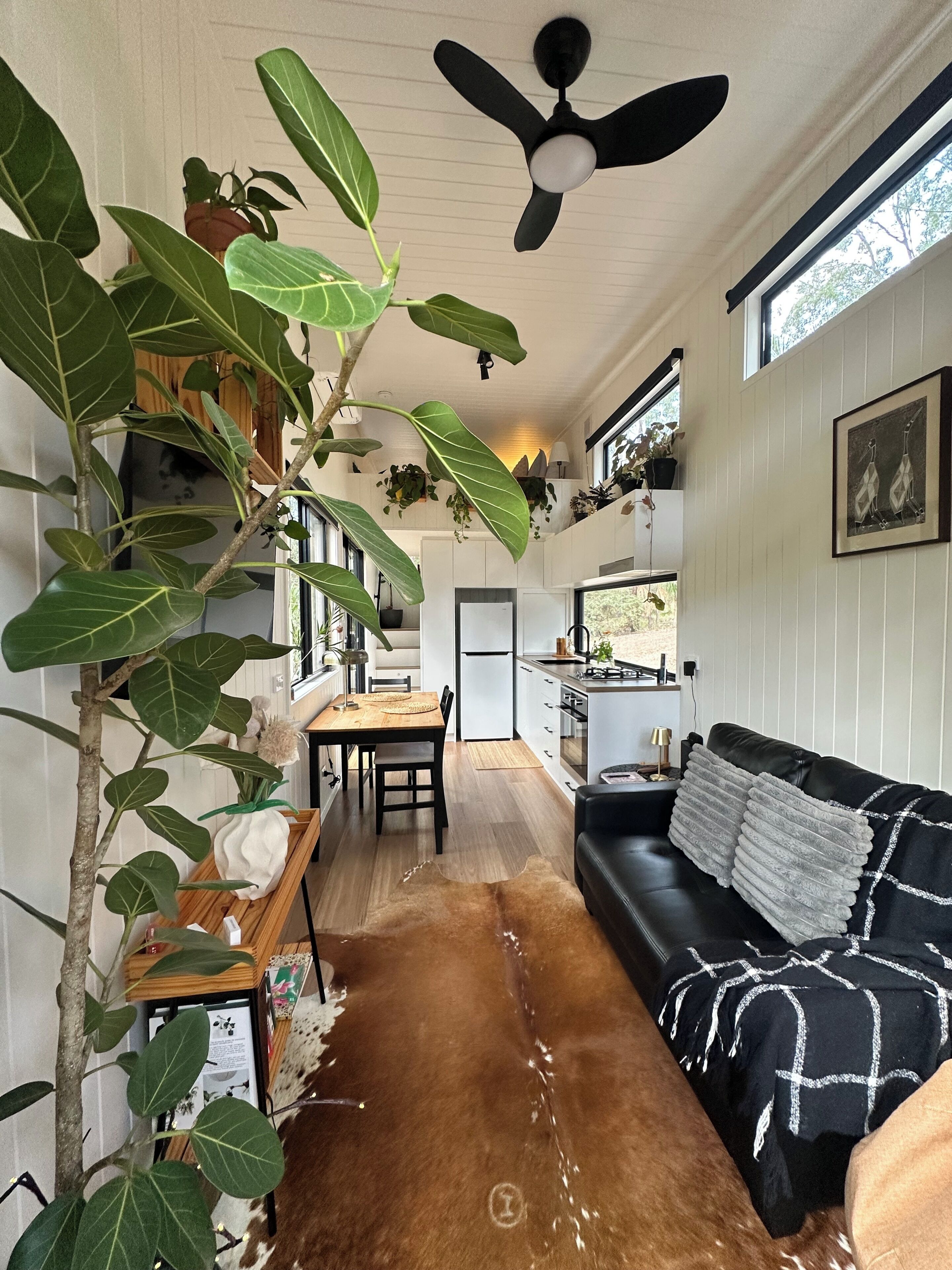 Une cuisine moderne avec des armoires blanches, un comptoir noir et un ventilateur de plafond.