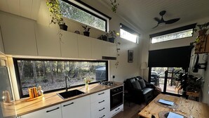 Eine moderne Küche mit weißen Schränken, einer Holzauskładung und einem großen Fenster mit Blick auf einen Wald.