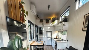 Eine moderne Küche mit Essbereich, einem schwarzen Sofa und einer großen Pflanze.