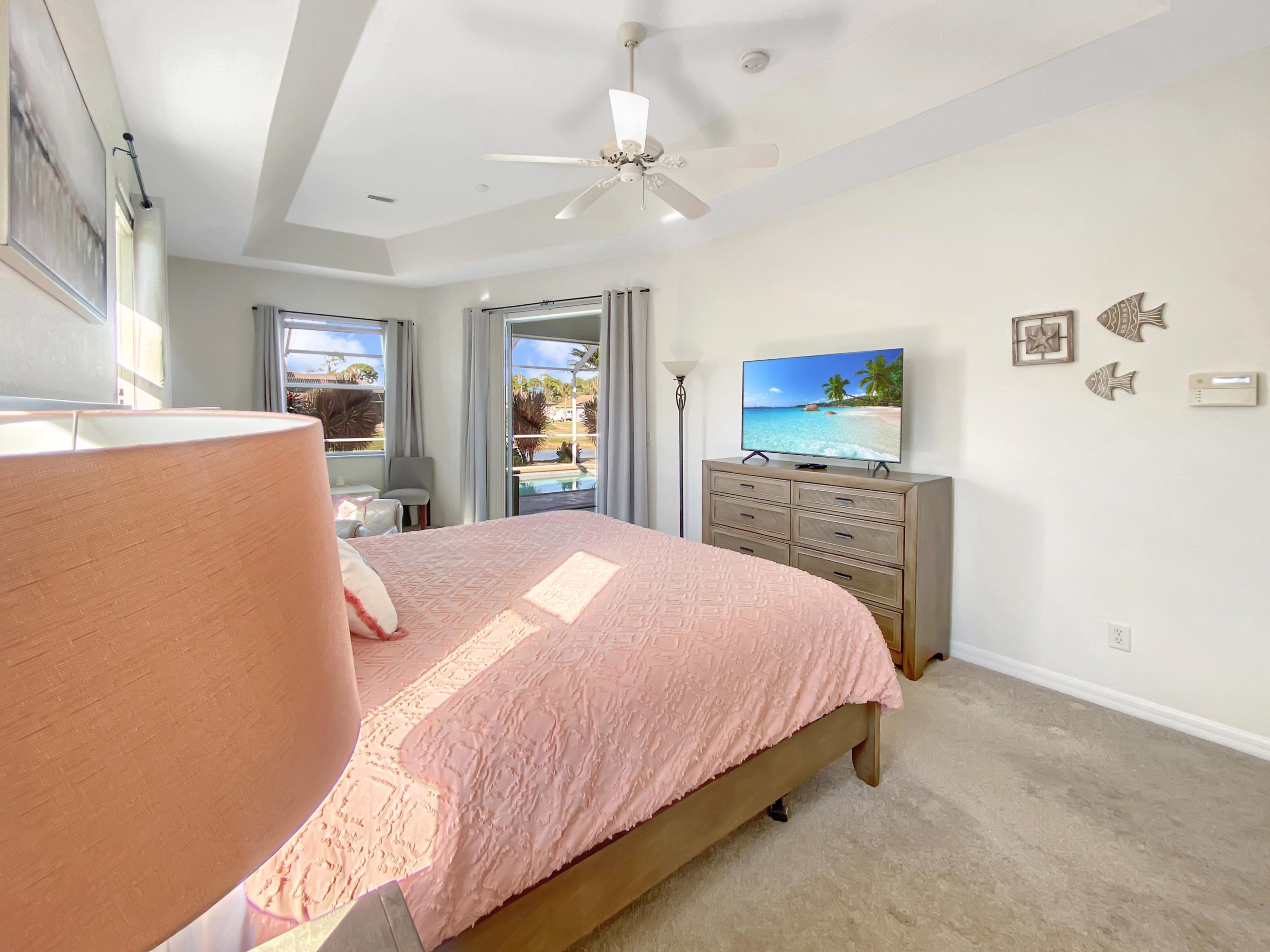 Une chambre à coucher avec un lit, une télévision, un ventilateur de plafond et une vue sur l’extérieur.