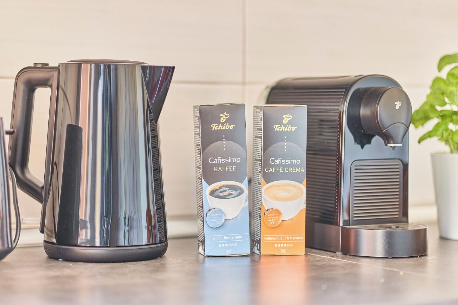 Eine Küche mit Kaffeemaschine, Kaffeekanne und zwei Packungen Kaffeekapseln.