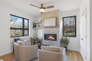 A modern living room with a fireplace, large windows, and a ceiling fan. - Modern 4 Bedrooms with 4 Ensuite Bathrooms - Perfect for Families & Groups (Riverside)
