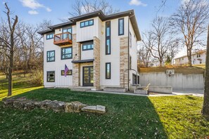 A modern two-story house with a balcony, a flag, and a basketball hoop in the yard. - Modern 4 Bedrooms with 4 Ensuite Bathrooms - Perfect for Families & Groups (Riverside)