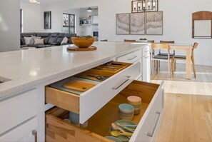 A modern kitchen with a large island, built-in drawers, and a dining area with wooden chairs. - Modern 4 Bedrooms with 4 Ensuite Bathrooms - Perfect for Families & Groups (Riverside)