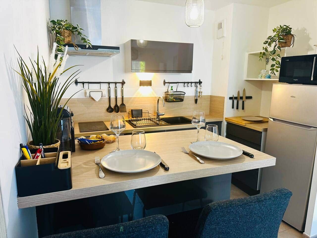 Une cuisine moderne dotée d’un îlot central, d’appareils électroménagers en acier inoxydable et d’un porte-ustensiles suspendu.