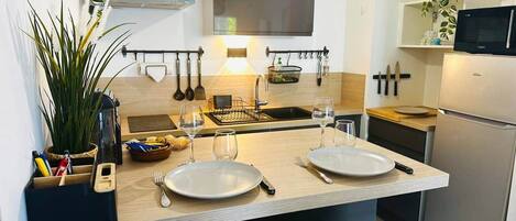 A modern kitchen with a central island, stainless steel appliances, and a hanging pot rack.