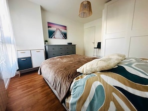 A bedroom with a bed, a dresser, a wardrobe, and a painting on the wall. - Urban cocoon, quiet studio 2 minutes from Vannes (Plescop)