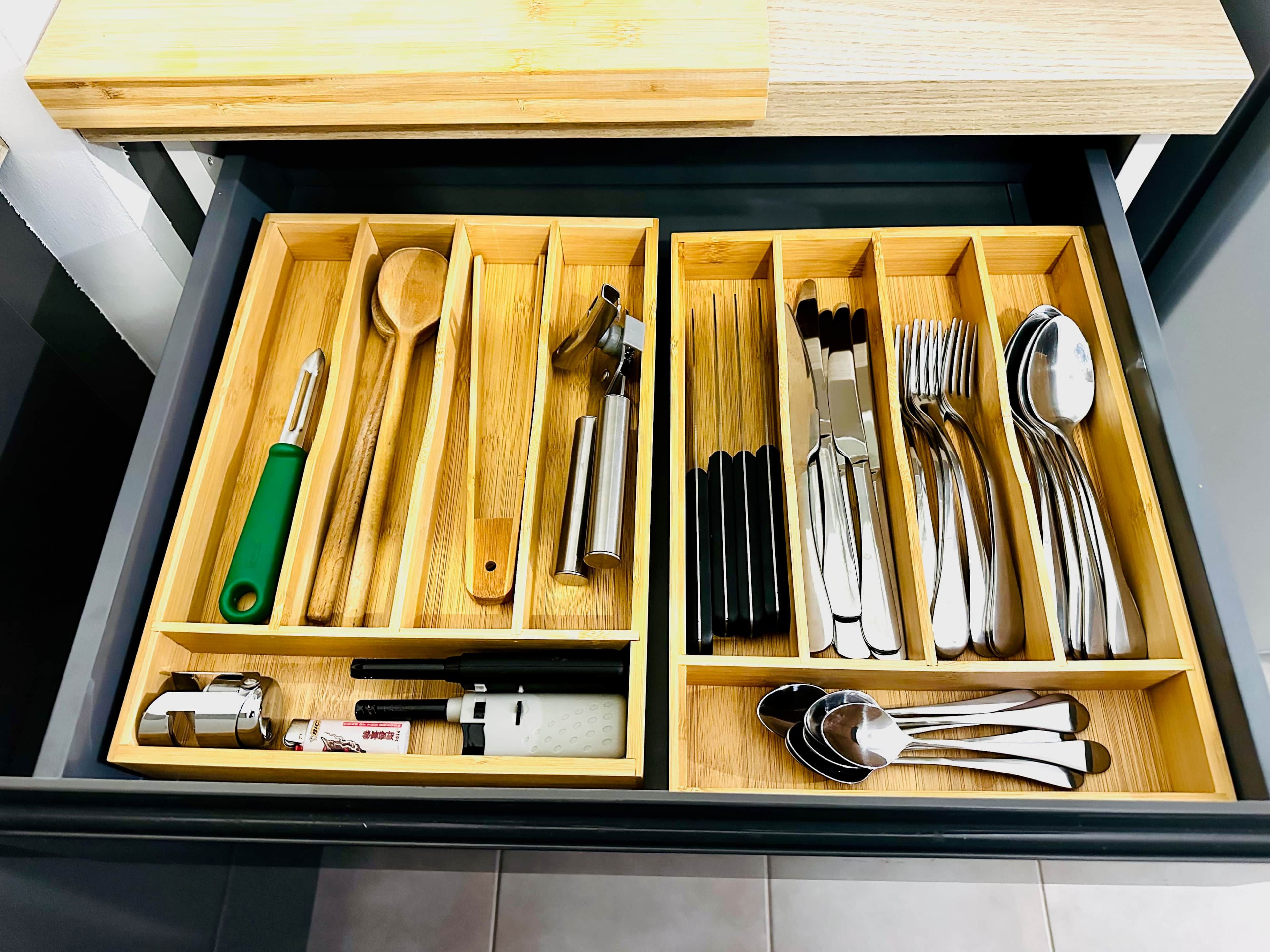 A drawer with compartments containing various kitchen utensils and tools.