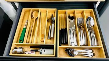 A drawer with compartments containing various kitchen utensils and tools.