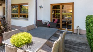 Eine Terrasse mit Tisch, Stühlen, einem Blumentopf und einer Tür mit Blick.