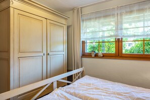 Une chambre avec un lit, une fenêtre donnant sur un espace verdoyant et une armoire.