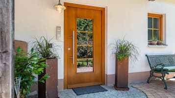 Une porte en bois avec un panneau de verre, un banc et des plantes en pot.