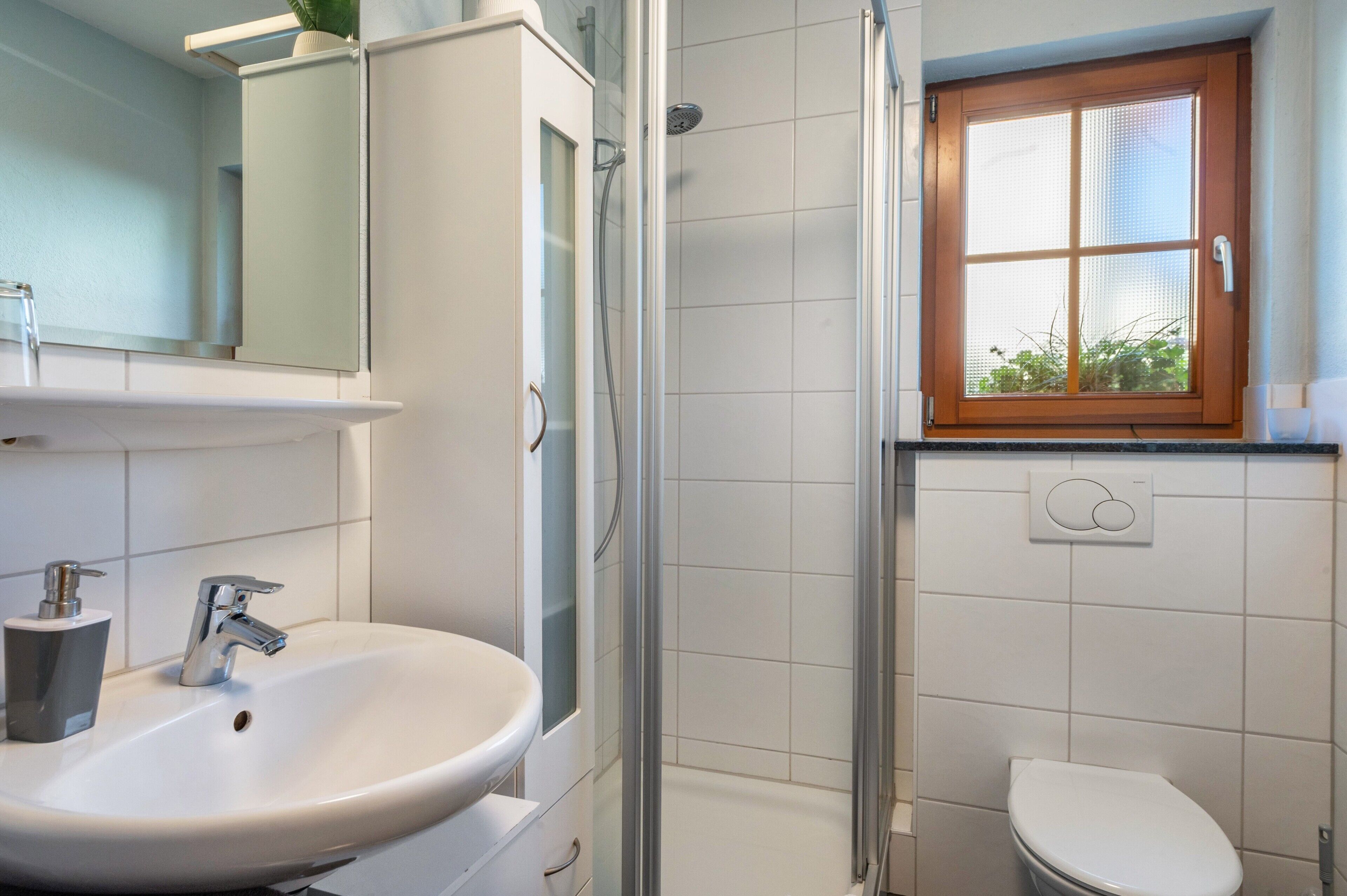 Ein Badezimmer mit Waschbecken, Spiegel, Duschkabine und Toilette.