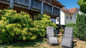 Een tuin met twee stoelen en een gebouw met balkon.